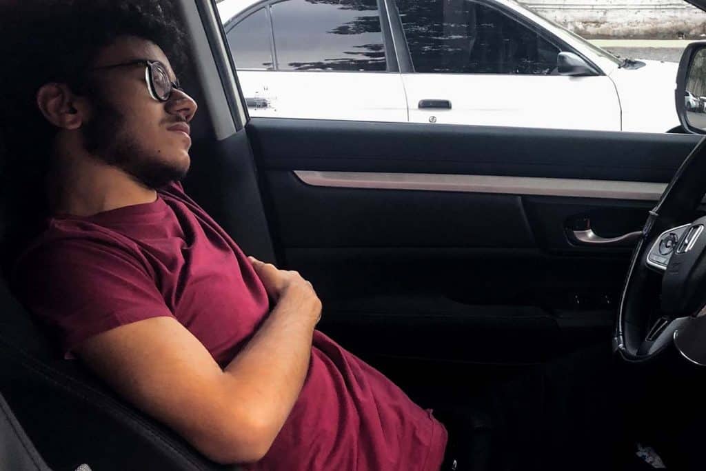 Men sleeping in a car with a red wine t-shirt